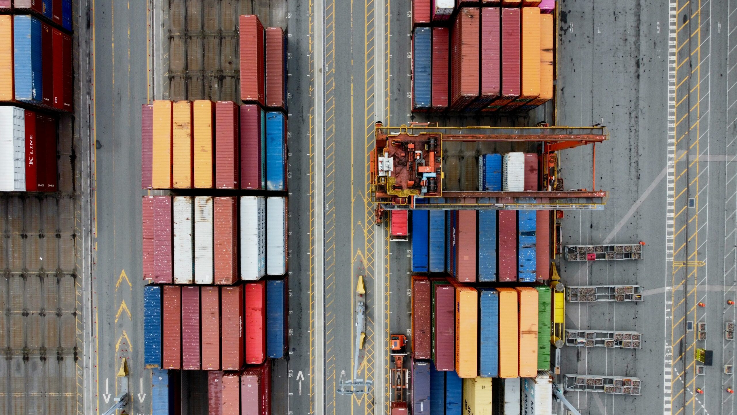 Vista dall’alto di container impilati in un terminal portuale.